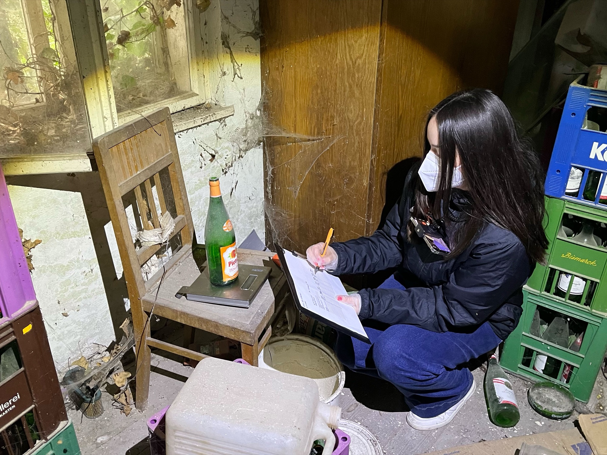 Taking notes on site, crouching among old bottle crates