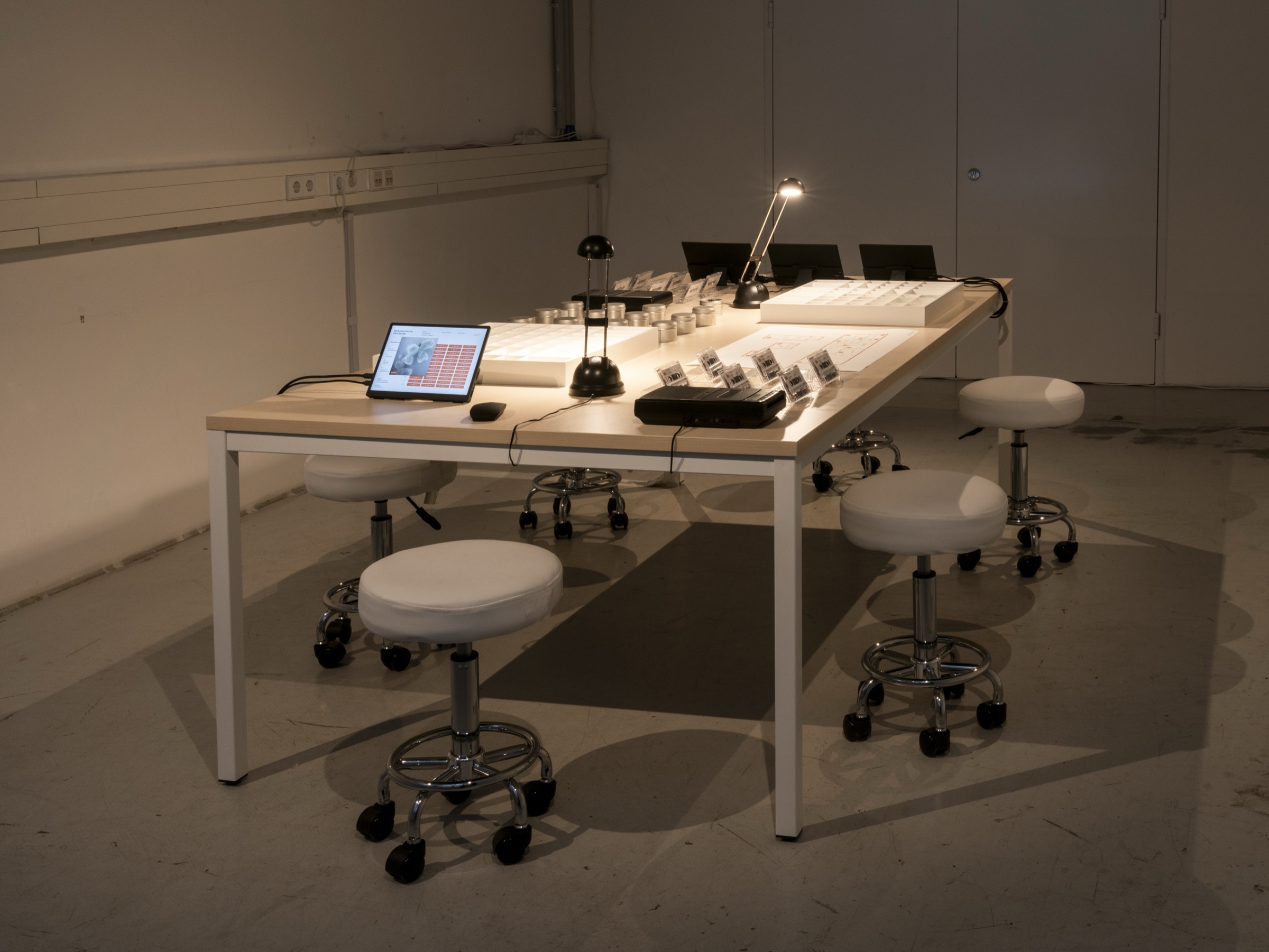 The Inventur installation: a long table with tablets, lamps, cassettes and sample tins